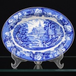 FAIANÇA INGLESA, uma (1) travessa oval de borda alta, ornamentação dita FAZENDINHA, representando paisagem rural, borda com barrado floral, tonalidade azul sobre fundo branco, marca WOOD & SONS (fundada em 1865, funcionou na Potteries New Wharf em Trent e mais tarde na Pottery Stanley em Burlem, fechou em 2005), medindo 22 x 16,5 x 5 cm, vide foto.