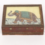 DIVERSOS, uma (1) caixa retangular confeccionada em madeira, tampa com pintura em vidro em policromia representando elefante, apliques em metal na técnica pique, com perdas em um lado da tampa, interior com forração em tecido aveludado na tonalidade vinho, medindo 13 x 10,5 x 3,5 cm, vide foto.