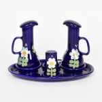 FAIANÇA, um (1) conjunto galheteiro com: 1 bandeja (bicadinhos na borda); 2 galhetas e 1 polvilhador, faltando outro, ornamentação floral policromada sobre fundo azul cobalto, sem marca de manufatura aparente, medindo a maior peça 23 x 14 cm, vide foto.