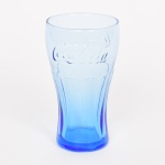 VIDRO, um (1) copo azul e translúcido, moldado com propaganda da COCA-COLA, marca CISPER (Companhia Industrial São Paulo e Rio; em 1916 a Companhia Vidraria Carmita, fundada em 1908 no Rio de Janeiro, entrou em falência, Olavo Egídio de Sousa Aranha Júnior, maior credor da empresa, adquiriu o maquinário e fundou a CISPER em sociedade com Alberto Monteiro Carvalho; em 1949 inaugurou a segunda fábrica em São Paulo; em 1962 vendeu 79% da empresa para a Owens-Illinois Incorporation; em 2011 vendeu os 21% restantes), medindo 15 cm altura, vide foto.