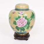 CLOISONNÉ, um (1) vaso bojudo com tampa, ornamentação esmaltada em policromia representando flores, nuvens e borboleta, peanha em madeira torneada, entalhada em vazados e ebanizada, altura total 23 cm, vide foto.