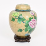CLOISONNÉ, um (1) vaso bojudo com tampa, ornamentação esmaltada em policromia representando flores, nuvens e borboleta, peanha em madeira torneada, entalhada em vazados e ebanizada, altura total 23 cm, vide foto.