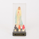 ARTE SACRA, um (1) grupo escultórico retratando a aparição de Nossa Senhora de Fátima, confeccionada em polímero policromado, redoma incolor e translúcida, medindo 12,5 cm altura, vide foto.