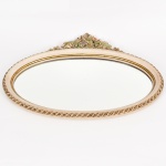 ESPELHO, um (1) oval para fixação em parede de cristal bisotado, moldura em madeira relevada em perolados e corda, encimada por talha relevada em volutas e elementos vegetalistas, medindo 80 x 60 cm, vide foto.