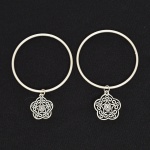 BIJUTERIA, duas (2) pulseiras de argola com penduricalhos vazados em flores estilizadas, confeccionadas em metal prateado, medindo 6,5 cm diâmetro, vide foto.