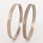 JOIAS, par (2) pulseiras lisas, com frisos diagonais, confeccionadas em PRATA, contrastadas 925 milésimos, medindo 6,5 cm diâmetro, peso total aproximado 21 gr., vide foto.
