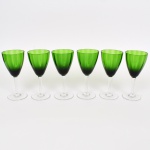 VIDRO, seis (6) taças de pé anto para água, bojo na tonalidade verde com ligeiro canelado na vertical, fuste hexagonal afinando para baixo, base em bolacha, ambos incolores e translúcidos, uma com bicado na borda, medindo 17,5 cm altura, vide foto.