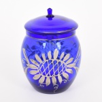 VIDRO, um (1) pote ligeiramente bojudo com tampa, tonalidade azul cobalto, translúcido, ornamentação vegetalista em prata com sinais de desgastes, medindo 15,5 cm altura, vide foto.