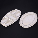 AÇO INOX, dois (2) itens, ambos confeccionados na técnica de estamparia mecanizada e sem marca de manufatura aparente, sendo: 1 travessa oval com borda plissada, medindo 41 x 27,5 cm; 1 petisqueira com divisórias, medindo 45 x 25 cm, vide foto.