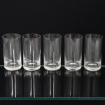 CRISTAL, cinco (5) copos cilíndricos, incolores e translúcidos, marca STRAUSS em acidado na base, duas com bicados na borda, medindo 12 cm altura e 6 cm diâmetro, vide foto, acondicionados na caixa.