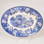 FAIANÇA INGLESA, uma (1) travessa oval com ornamentação dita FAZENDINHA, representando paisagem rural, borda com barrado floral, tonalidade azul sobre fundo branco, marca WOOD & SONS (fundada em 1865, funcionou na Potteries New Wharf em Trent e mais tarde na Pottery Stanley em Burlem, fechou em 2005), craquejados e manchas, medindo 22,5 x 17,5 cm, vide foto.