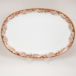 PORCELANA, uma (1) travessa ovalada, ornada com faixa marrom e barrado vegetalista, arremates com frisos a ouro, modelo MON CHERI, marca RENNER (Porto Alegre, RS, fundada em 1942; em 1998 foi vendida para a Vista Alegre de Portugal; em 1999 mudou a razão social para Vista Alegre do Brasil), medindo 36 x 24,5 cm, vide foto.