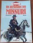 HQ Rara: A Juventude de Blueberry  Os Demónios do Missuri  Ed. Meribérica/LiberEste álbum é historicamente marcante para o colecionismo por ser o primeiro da sub-série em que Jean Giraud (Moebius) passa o bastão dos desenhos para o talentoso Colin Wilson, mantendo o roteiro afiado do criador original J.M. Charlier. Ambientada no ápice da violenta Guerra Civil Americana, a trama mergulha Blueberry em uma atmosfera brutal na fronteira do Missouri contra forças guerrilheiras impiedosas. As edições desta linha impressas pela saudosa editora Meribérica são raridades cobiçadas devido à sua baixa tiragem remanescente e refinada qualidade gráfica.