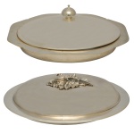 Conjunto de dois grandes pratos cobertos para servir de formato oblongo em metal prateado. Ambos possuem pegadores decorativos no topo da tampa para facilitar o manuseio. 17 x 43 x 32 cm e 14 x 42 x 31 cm.