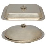 Conjunto de dois pratos cobertos para servir em metal prateado, sendo um retangular e outro oblongo. Ambos possuem pegadores decorativos no topo da tampa para facilitar o manuseio. 18 x 50 x 38 cm e 12 x 46 x 32 cm.