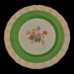 RIDGWAYS, Shelton. Inglaterra - Prato circular em louça inglesa.  Centro decorado com um arranjo floral policromado e borda ondulada com anel verde característico e detalhes em dourado na borda. Marca da manufatura no verso. 28 cm.