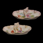 Par de covilhetes em porcelana com alça central e delicada decoração floral com detalhes dourados. 7 x 17 x 9 cm.