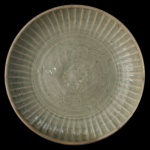 Medalhão circular em porcelana chinesa, revestido por coberta celadon de cor verde. Apresenta decoração com gomos, centralizando rosácea floral emoldurada por estilizações. Verso apresentando marca com carimbo China. Peça do séc. XX no estilo da dinastia Ming.  7 x 35 cm.