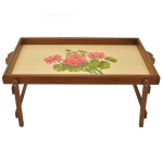 Bandeja com pés dobráveis, em madeira. Formato retangular e decorada no centro com pintura floral de gerânios cor-de-rosa. Marca Old Factory. 5 x 66 x 40 cm (fechada). 25 x 66 x 40 cm (aberta).
