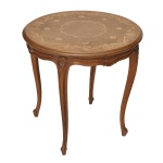 Mesa lateral redonda em madeira clara. Exibe um sofisticado tampo com trabalho em marchetaria e composição central em gomos de madeira nobre combinada com um elaborado medalhão e arabescos florais claros ao redor da borda. Elegantes pernas cabriolé arqueadas em formato de "S") que afinam em direção aos pés, 55 x 55 cm. Apresenta desgastes do tempo.