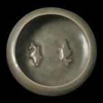 Tigela lava pinceis circular em porcelana chinesa, revestida por coberta celadon de cor verde oliva com discreto craquelê. Bojo liso e revirado. Apresenta ao fundo casal de peixes aplicados em leve relevo. Base apoiada em 3 pequenos pés. 5 x 14 cm. Peça decorativa e de design moderno