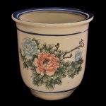 Cachepot em porcelana oriental decorado com uma pintura floral rica em detalhes. Destaca-se uma grande flor central em tons de salmão e flores secundárias em azul claro, além de folhagens e galhos. Frisos azul nas  bordas superior e inferior. 20 x 19 cm.