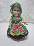Linda e antiga boneca com membros em porcelana, com corpo e roupa em tecido. Medindo 22cm de altura.