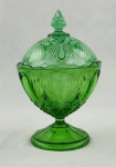 Compoteira de coleção em vidro na cor verde, decoração em relevo, com motivos geométricos, borda ondulada. Corpo apoiado sobre pé circular decorado. Medindo: 22 x 13 cm. apresenta lascas na tampa e bicados na borda. 