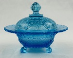 Manteigueira de coleção em vidro na cor azul, decoração em relevo, com flores e arabescos, bordas recortadas. Apoiado sobre três pés. Medindo: 13 x 15 cm. Apresenta bicados.