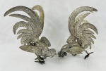 Par de galos de briga em metal cinzelado. Medindo: 22 x 28 x 22 cm e 25 x 20 x 15 cm. 