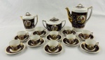 Vista Alegre, Portugal. Serviço para café em porcelana portuguesa decorado em tom vinho, com áreas de efeito marmorizado e detalhes em dourado. Apresenta reservas circulares com cenas figurativas de inspiração clássica, aplicadas em policromia. Composto de bule, leiteira, açucareiro e 10 xícaras com seus pires.  Manufatura no verso. 2 xícaras com fios de cabelo, 4 pires com pequenos bicados, bule com bicado no bico. 
