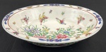 China. Saladeira em porcelana chinesa esmaltados com rica decoração policroma de motivos florais, folhagens e borboletas; detalhes em azul e bordô ao gosto Famille Rose. Marcado ao fundo em azul. Medindo: 5,5 x 26 x 20 cm.