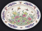 China. Travessa em Porcelana chinesa esmaltados com rica decoração policroma de motivos florais, folhagens e borboletas; detalhes em azul e bordô ao gosto Famille Rose. Marcado ao fundo em azul. Medindo: 34 x 25 cm