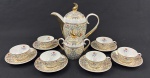 Schmidt. Conjunto para café em porcelana esmaltada e policromada, com delicada decoração floral sobre fundo furta-cor e ricos detalhes em ouro.  Composto de bule, açucareiro e 6 xícaras com seus pires. Manufatura no verso. Medindo: 20 x 20,5 cm e 12 x 12 cm.