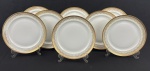 Limoges, France. Oito pratos rasos em porcelana esmaltada na cor branca com rica decoração em douração, composta por faixa ornamental de inspiração neoclássica, formada por reservas ovais com motivos florais estilizados, folhagens e arabescos, dispostos em composição rítmica e simétrica. Apresenta frisos e filetes concêntricos em ouro, acabamento de grande elegância e requinte. Manufatura no verso. Medindo: 24 cm. Alguns apresentam desgastes.