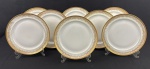 Limoges, France. Oito pratos rasos em porcelana esmaltada na cor branca com rica decoração em douração, composta por faixa ornamental de inspiração neoclássica, formada por reservas ovais com motivos florais estilizados, folhagens e arabescos, dispostos em composição rítmica e simétrica. Apresenta frisos e filetes concêntricos em ouro, acabamento de grande elegância e requinte. Manufatura no verso. Medindo: 24 cm.