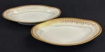 Limoges, France. Duas espinheiras em porcelana esmaltada na cor branca com rica decoração em douração, composta por faixa ornamental de inspiração neoclássica, formada por reservas ovais com motivos florais estilizados, folhagens e arabescos, dispostos em composição rítmica e simétrica. Apresenta frisos e filetes concêntricos em ouro, acabamento de grande elegância e requinte. Manufatura no verso. Medindo: 3 x 23 x 13 cm. Apresentam desgastes.