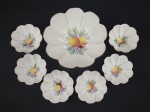 Saladeira e seis tigelas em porcelana nacional branca, de formato recortado e decoração floral com frutos policromados, apresentando filetes em dourado. Uma das tigelas com bicado. Medindo a saladeira: 10 x 21 cm e as tigelas: 5 x 10,5 cm.