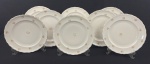 EPIAG. Oito pratos rasos em porcelana tcheca na cor marfim, com decoração floral policromada, detalhes na borda em relevo e filetes em ouro, manufatura no verso. Medindo: 24 cm.
