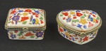 Duas caixas porta joias em porcelana na cor branca, esmaltada com policromia de flores e guarnições em plástico rígido. Medindo: 3,5 x 6 x 6 cm e 3,5 x 8 x 7 cm.