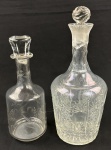 Duas licoreiras em cristal translúcido, ricamente lapidadas, tampas adaptadas e uma delas quebrada. Uma licoreira com batida seca. Medindo:27 e 33 cm.