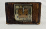 Antigo relógio de mesa com caixa em madeira de tonalidade castanha, apresentando acabamento e pátina decorrentes do tempo. Mostrador quadrangular protegido por vidro, com numeração arábica estilizada e ponteiros metálicos. Dimensões: 20 x 33 x 12,5 cm. Apresenta sinais de uso, desgaste e oxidação compatíveis com a idade da peça. Não testado, sem garantias de funcionamento.