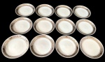Steatita - Doze pratos para pão em porcelana com aba decorada em tom prateado e detalhes em relevo formando cenas clássicas ao redor da borda. Filete fino próximo à área central. Medindo: 15 cm.