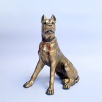 Escultura em metal branco com pátina dourada representando um Dogue Alemão. Med 19,5x16cmx9,5cm. 