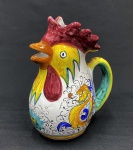 Tradicional jarra de porcelana italiana em formato de galo, pintada à mão no estilo majólica da região de DERUTA, na Úmbria, e frequentemente associada ao padrão decorativo Raffaellesco  Rooster,  que significa  galo da sorte.  Na tradição italiana presentear ou exibir uma jarra de galo simboliza prosperidade. Medindo: 22 x 18 x 11 cm.