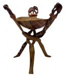 ARTE AFRICANA. Suporte de madeira entrelaçado em bloco de madeira único com pernas em tripé entrelaçado com pintura a mão de animais com uma tigela destacável ao centro. Forma um suporte dobrável, sem emendas, que segura a tigela decorada com padrões tribais e motivos de animais elefante esculpido no topo. Medindo: 32 x 23 cm, 39 cm.