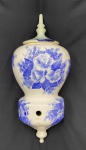WEISS. Antiga talha/filtro em porcelana branca com pintura floral azul para ser preso na parede. Possui tampa com cloração diferente. Marcas do tempo. Medindo: 50 x 21 x 22 cm.