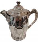 IMPERIAL SILVER PLATE. Bule em metal prateado, corpo liso de formato bojudo, base circular moldurada e tampa articulada com puxador ornamental. Alça e bico decorados com motivos florais e volutas em relevo, de inspiração Rococó. Marca na base e numeração 2581. Apresenta riscos superficiais e marcas do tempo. Medindo: 26 x 24 x 14 cm.