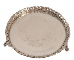 Pequena salva circular em metal espessurado a prata, centro decorado com ramagens gravadas, borda recortada e vazada com motivos florais e volutas em relevo, apoiada sobre três pés ornamentados. Apresenta riscos superficiais. Medindo: 2,8 x 14 cm.