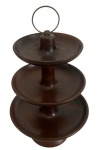 Antiga fruteira em madeira torneada, composta por três pratos circulares sobrepostos, de diâmetros decrescentes e bordas elevadas, unidos por haste central, com base circular e alça superior em argola de metal. Apresenta riscos e desgaste no acabamento. Medindo: 39 x 23,5 cm.